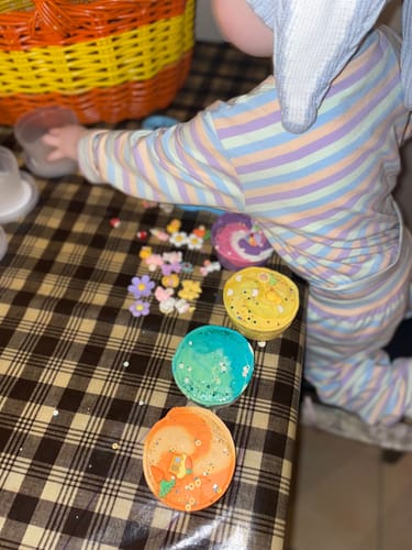 Customer's toddler wearing the colorful Pastel Stripe PJ Set while doing an Easter craft.