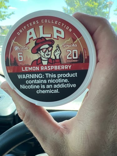 Customer holding a white can of ALP Drifters Lemon Raspberry nicotine pouches in their hand.