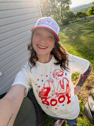 Reviewer smiling outdoors while wearing the Sorry About My Husband foam trucker hat.