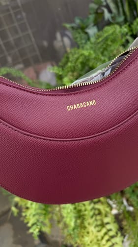Primer plano del bolso Rachel Maroon de un cliente, mostrando la textura y la marca dorada.