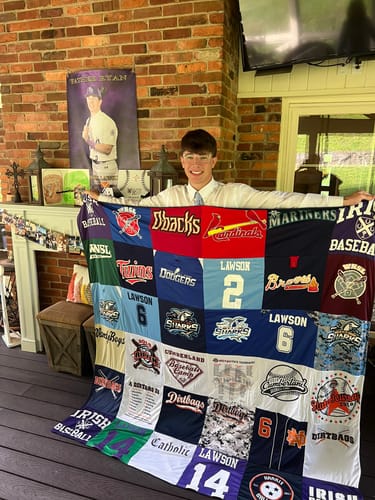 Customer holding up a large Project Repat T-Shirt Quilt made from a collection of youth baseball jerseys.