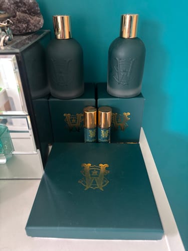 Customer's collection of De La Mer perfume, with large and travel-size bottles displayed with their dark green boxes.