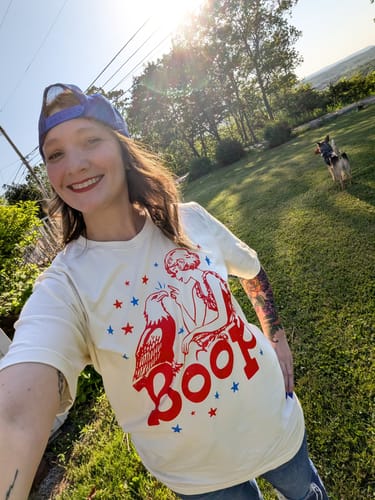Customer wearing the off-white Eagle Boop Tee outdoors in a sunny yard.