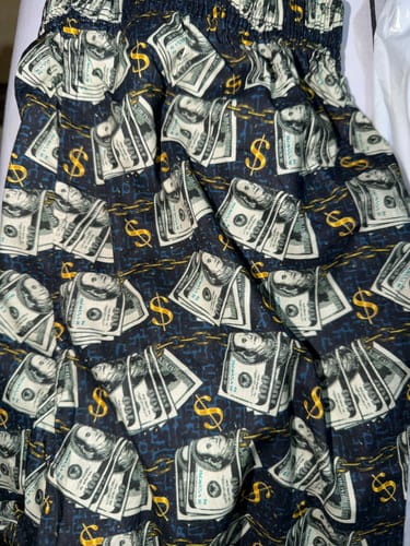 Reviewer photo of dark shorts with a bold pattern of dollar bills and signs.