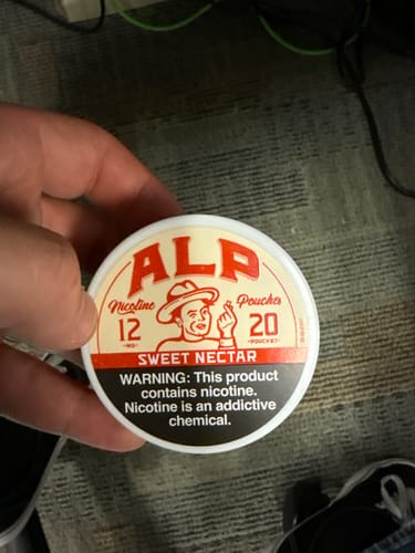 Customer holding a white and red tin of Sweet Nectar Nicotine Pouches.