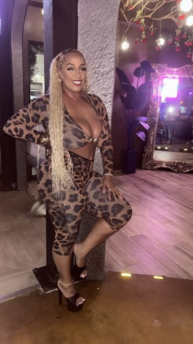 Customer posing indoors in the leopard print Naked Print Cutout Capri Jumpsuit and a matching headband.