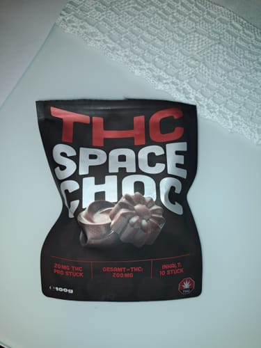 Kunde zeigt die schwarze Verpackung der THC SpaceChoc auf einer weißen Oberfläche.