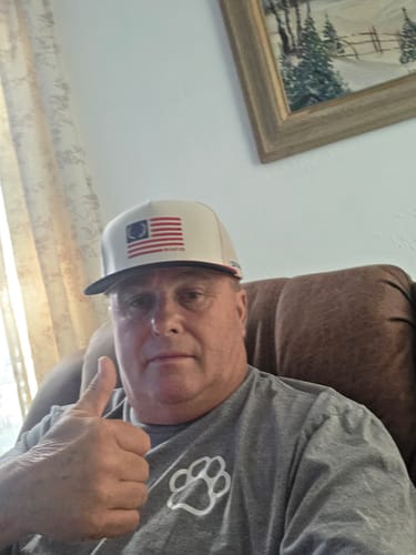 Reviewer wearing the Hat of the Month with an American flag patch, giving a thumbs up.