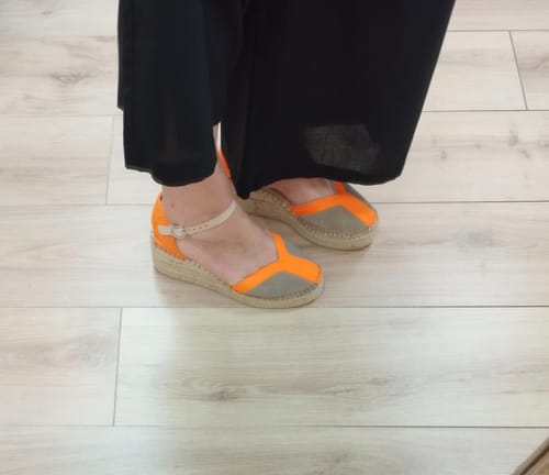 Cliente lleva puestas las alpargatas Nora Naranja, mostrando su diseño en colores naranja y piedra.