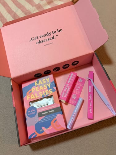 Eine Kundin zeigt die geöffnete rosa Box des Starter Set – Pre-Glued 2.0 mit dem gesamten Inhalt.