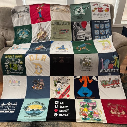 Customer's colorful Project Repat T-Shirt Quilt made with Disney-themed shirts, shown draped over a living room couch.