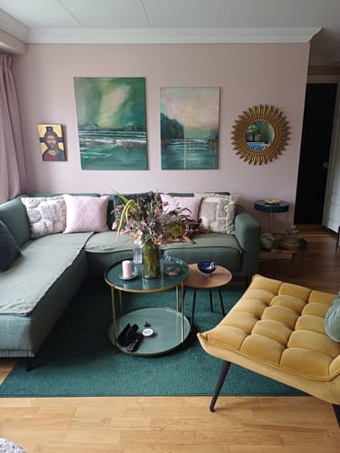 Kundens rosa putetrekk i bomull på en grønn sofa i en stue.