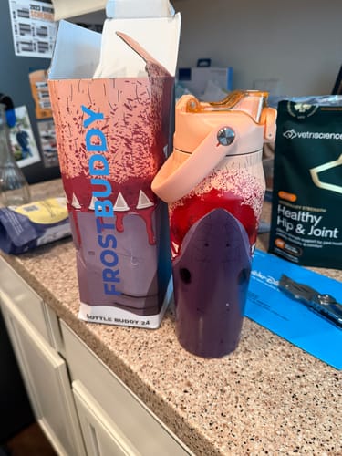 Customer's shark-themed Bottle Buddy 24oz with a purple boot, shown on a counter next to its original packaging.