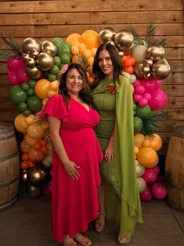 Reviewer standing with a friend at an event while wearing the green Chiffon Cape Crop Top with its flowing cape.