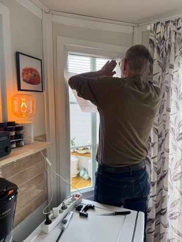 En anmelder som monterer Jalousie vindusfolie på et vindu.