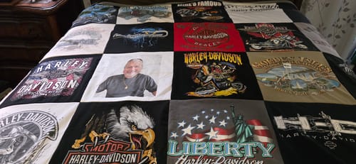 Customer's Project Repat T-Shirt Quilt made from Harley-Davidson shirts, including a photo square, spread across a bed.