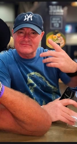 Customer wearing the blue Blowing Wishes T-Shirt while seated indoors.