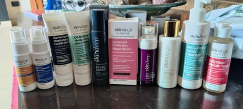 Reviewer's Advanced PDRN Skin Repair Serum in its box, lined up with a full routine of other skindeep products on a table.