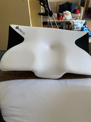 Photo d'un client montrant l'Oreiller Papillon Cervical Cellsius blanc et noir sur un lit.