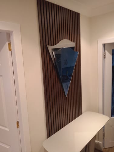 Reviewer's walnut acoustic wall panels installed as an accent in a hallway, styled with a modern mirror and console table.