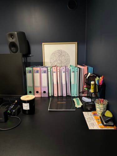 Utilisateur montrant sa collection de classeurs à anneaux OXFORD pastel, alignés sur un bureau.