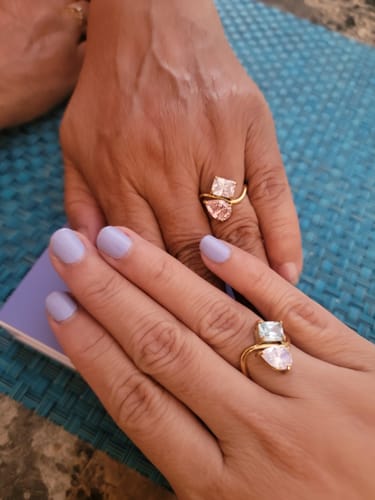 Close-up of two hands showing off their Navae Birthstone Rings, each with unique colorful stones.