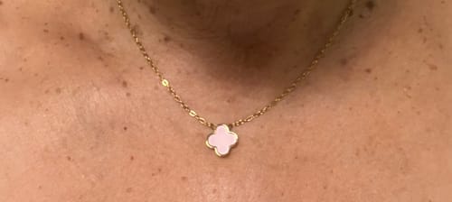 Eine Kundin trägt die Baby Pink Clover Kette mit einem rosa Anhänger am Hals.