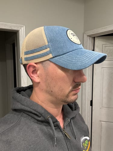 Reviewer showing a side profile of the blue denim and tan mesh Big Unstructured Trucker Hat.