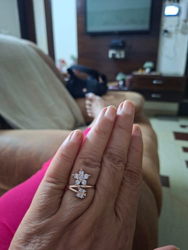 Customer's hand wearing a flower-shaped ring with sparkling stones and leaf details.