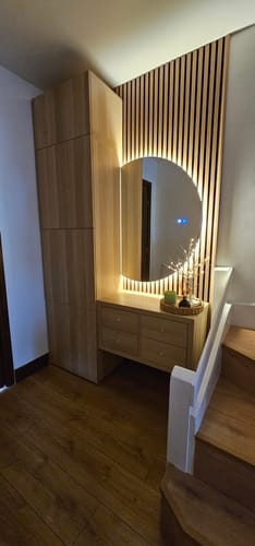 Customer's acoustic slatted wall panels installed in a hallway, creating an accent wall behind a modern backlit mirror.