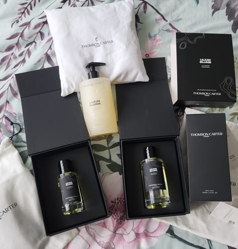 Customer's two bottles of Lilium Blume Eau de Parfum in elegant black boxes, next to a body wash and branded pouches.