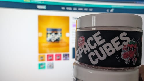 Ein Kunde hält seine Dose THC Space Cubes vor dem Computerbildschirm mit der Produktseite.
