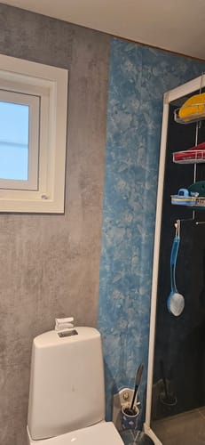 Kundens bilde som viser påføring av Mikrosement kontaktplast over en eldre, blå baderomsvegg.