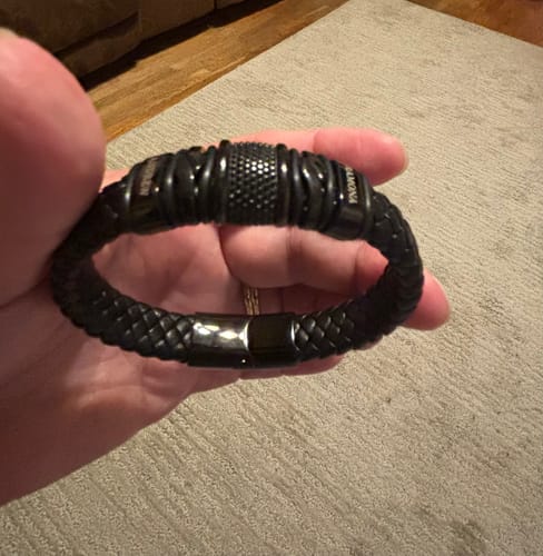 Reviewer holding the complete black bracelet, showing the braided band, personalized beads, and clasp.
