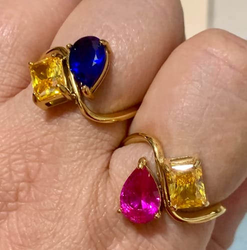 Customer wearing two gold Navae Birthstone Rings, one with blue and yellow gems and the other with pink and yellow gems.