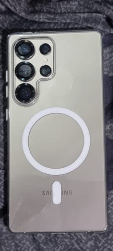 Customer's silver phone in a clear case with a white magnetic ring on the back, lying on a patterned surface.