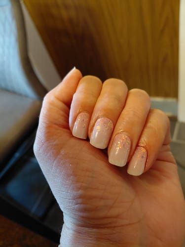Hand einer Kundin mit den 'Babyboomer Princess' UV-Gelnägeln. Sie haben einen zarten Farbverlauf und eleganten Glitzer.