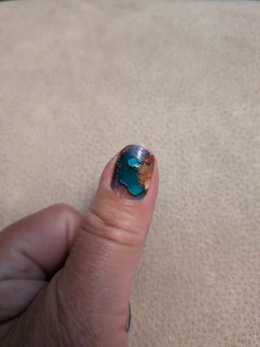 Eine Kundin zeigt die „Rock My World“-Nagelfolie auf ihrem kurzen, gepflegten Daumennagel.