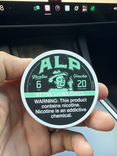 Customer holding a round tin of ALP Refreshing Chill Nicotine Pouches in their hand.