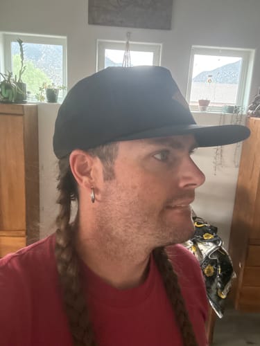 Reviewer showing the side profile fit of the black Big Flat Bill Wicking Hat.