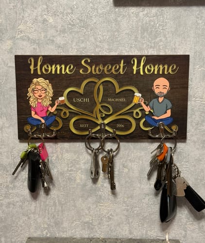 Personalisiertes 'Home sweet home'-Schlüsselbrett eines Kunden, das mit Schlüsseln behängt an einer Wand montiert ist.