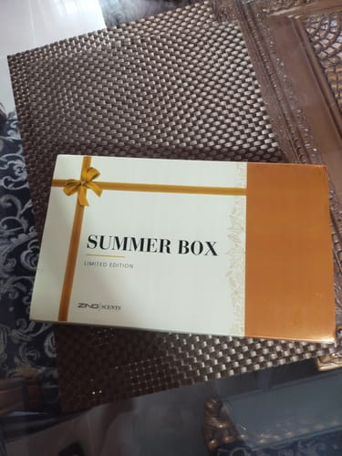 Customer's white and gold Summer Box, shown resting on a dark textured placemat.