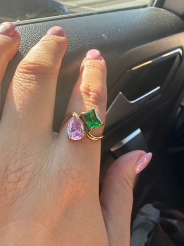 Customer's hand wearing the Navae Birthstone Ring with vibrant pink and green stones.