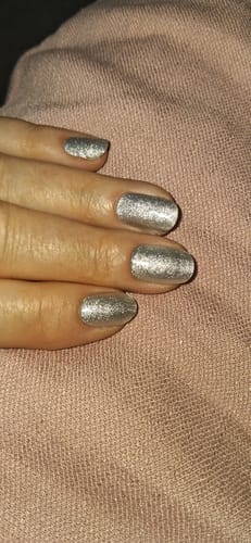 Nahaufnahme der Hand einer Kundin mit manikürten, silbernen Glitzernägeln.