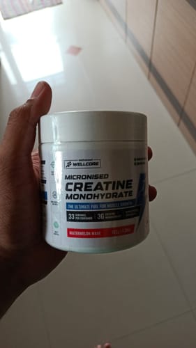 Customer holding a white tub of Wellcore Micronised Creatine Monohydrate in the Watermelon Wave flavor.