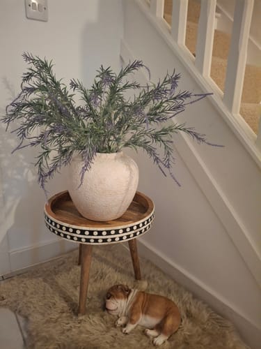 Customer's beige Naomi Ceramic Vase with faux lavender flowers on a small table in their home.