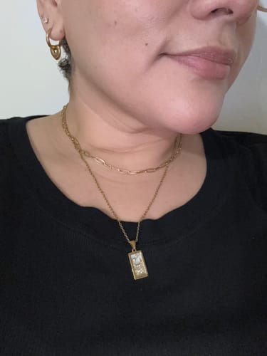 Close-up of a reviewer wearing pieces from the WaterProof Jewelry Bundle, including layered gold necklaces and a hoop earring.