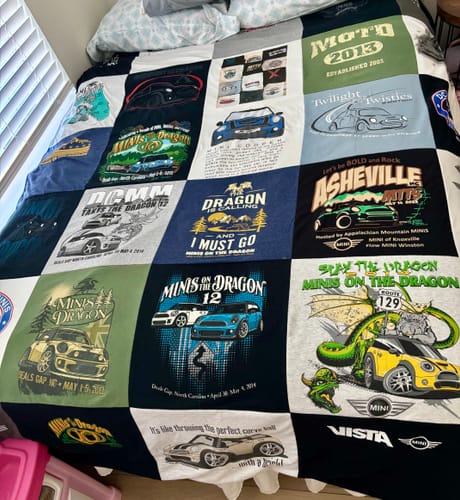 Customer's Project Repat T-Shirt Quilt made from colorful car-themed t-shirts spread across a bed.