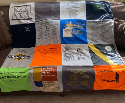 Customer's T-Shirt Quilt made with colorful high school band shirts, spread across a couch.