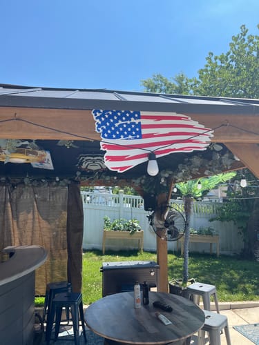 Customer's Tattered American Flag metal wall art mounted on a wooden gazebo outdoors.